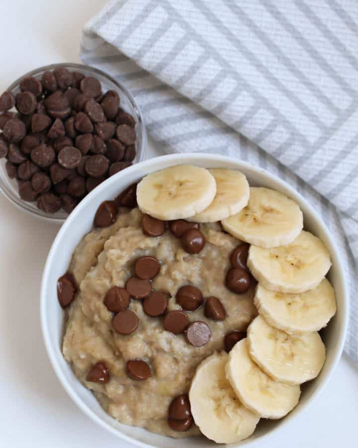 a bowl of peanut butter banana oatmeal with bananas and chocolate chips on top