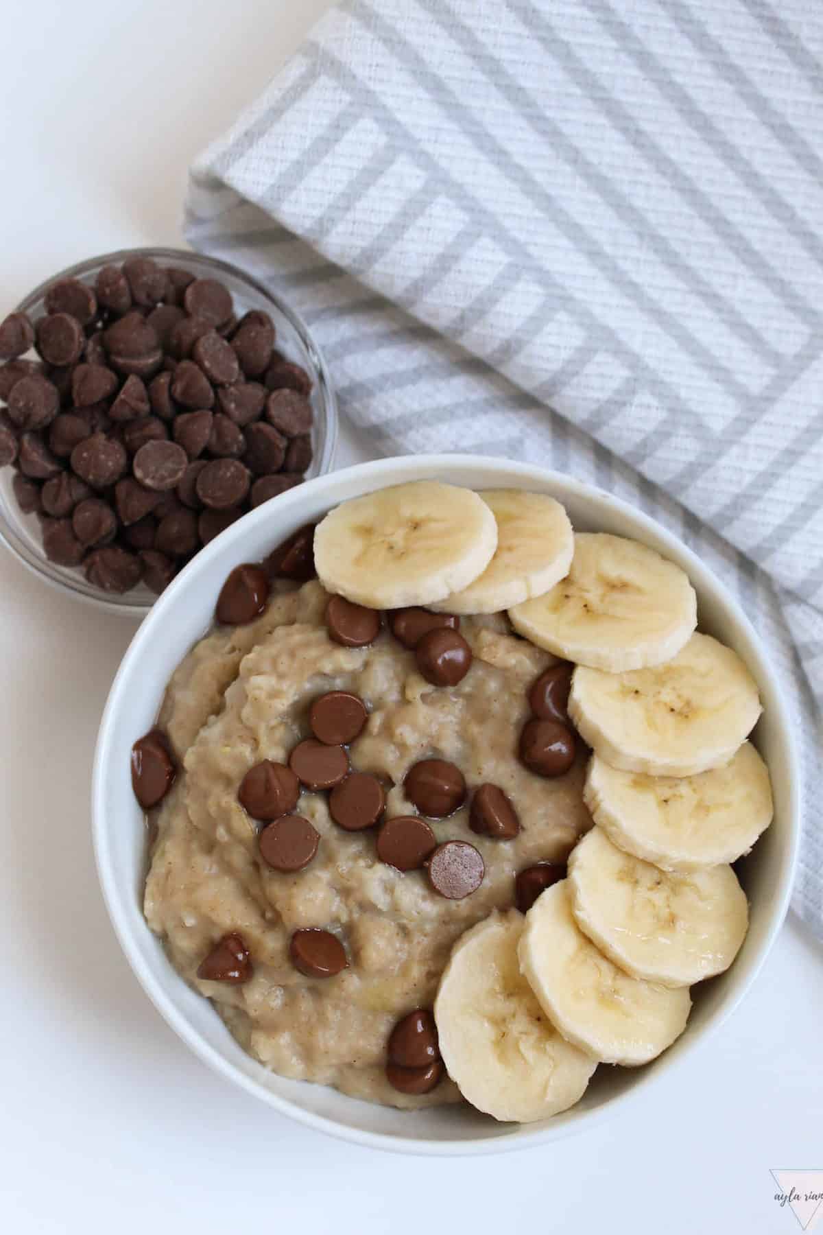 a bowl of peanut butter banana oatmeal with bananas and chocolate chips on top