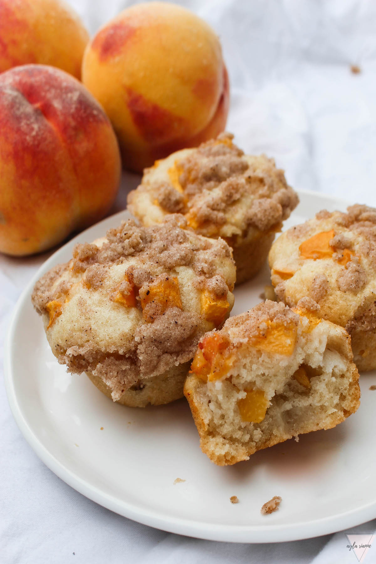 a plate of peach muffins with peaches in the background