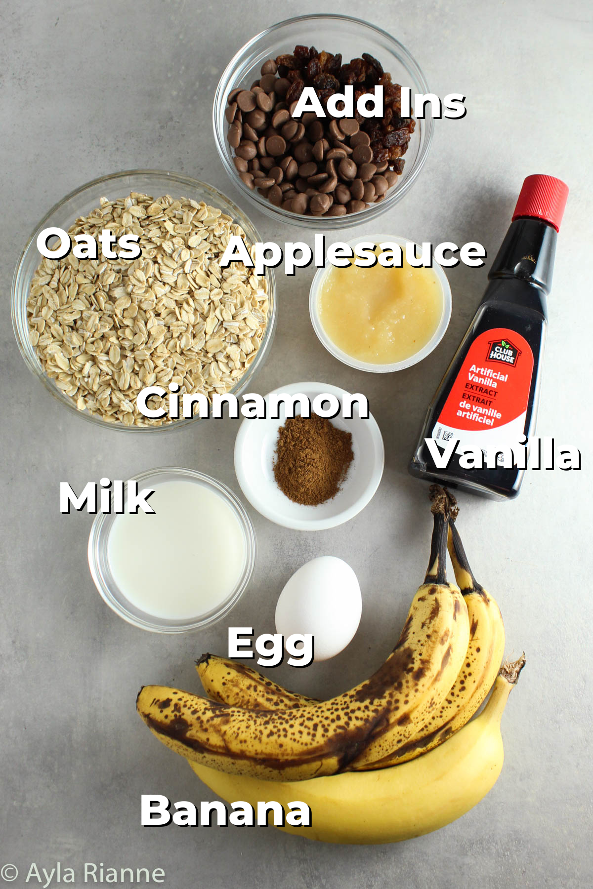 labelled ingredients for banana breakfast cookies including addins, oats, applesauce, vanilla, cinnamon, milk, egg, and bananas