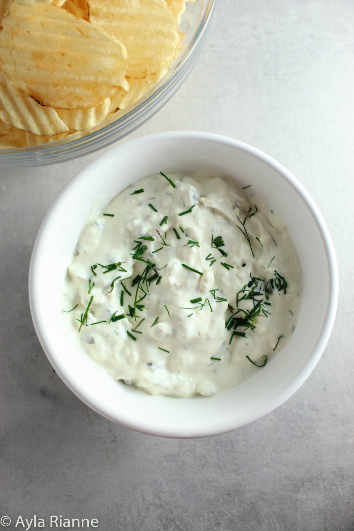 bowl of dill pickle dip with chips in background