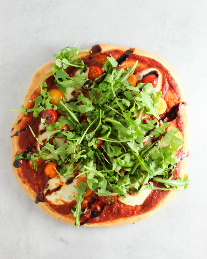 arugula pizza on a grey countertop