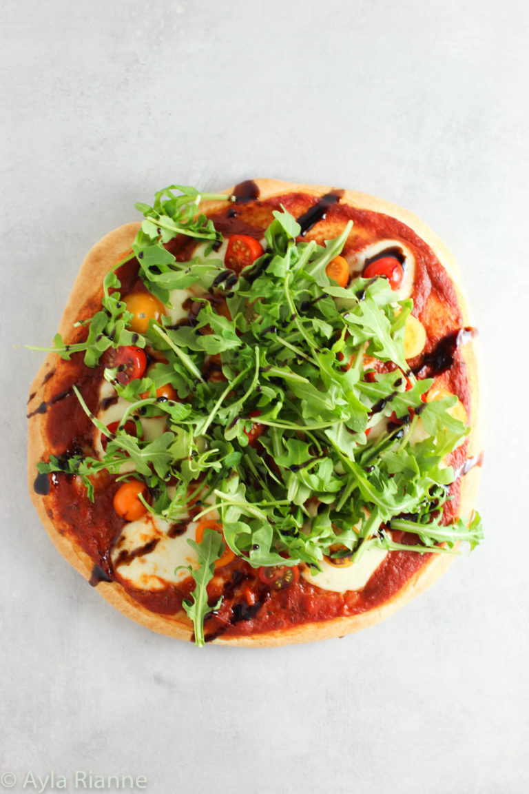 arugula pizza on a grey countertop