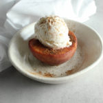 a baked peach with ice cream in a bowl