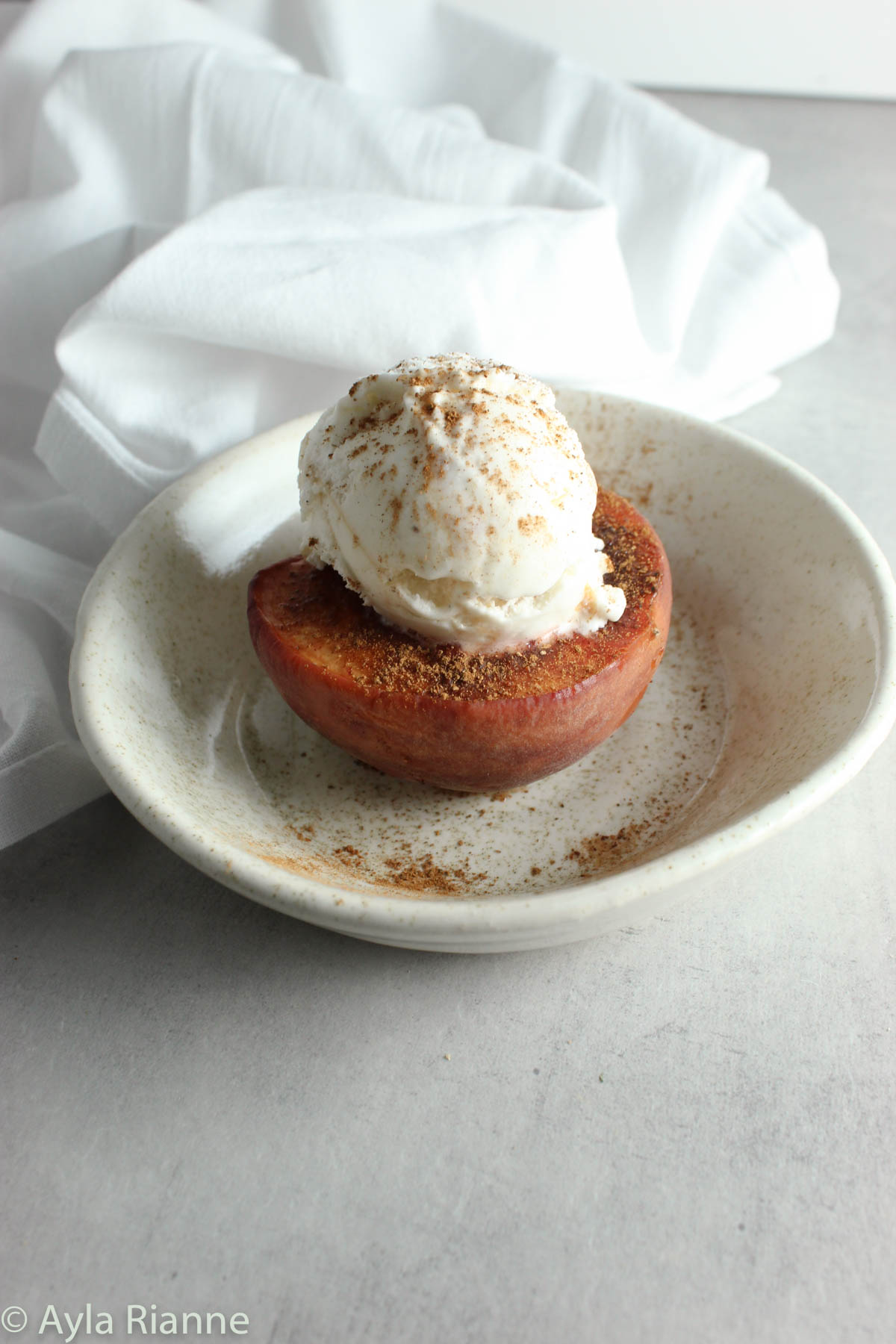 a baked peach with ice cream in a bowl