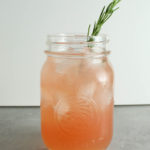 rosemary grapefruit drink in a mason jar with a rosemary sprig