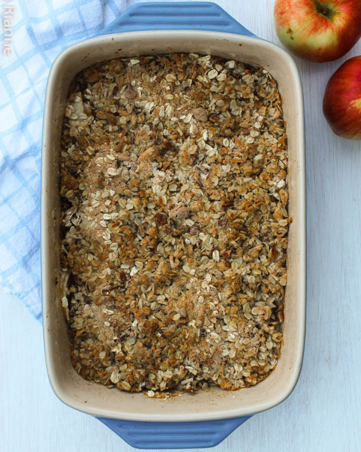 apple crisp in a blue dish with apples in the background