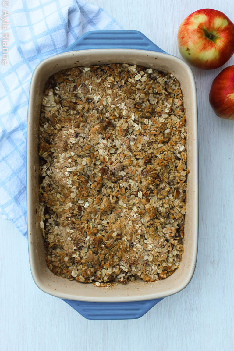 apple crisp in a blue dish with apples in the background
