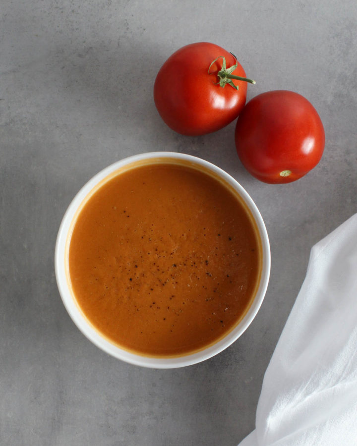 a bowl of tomato soup with two tomatoes