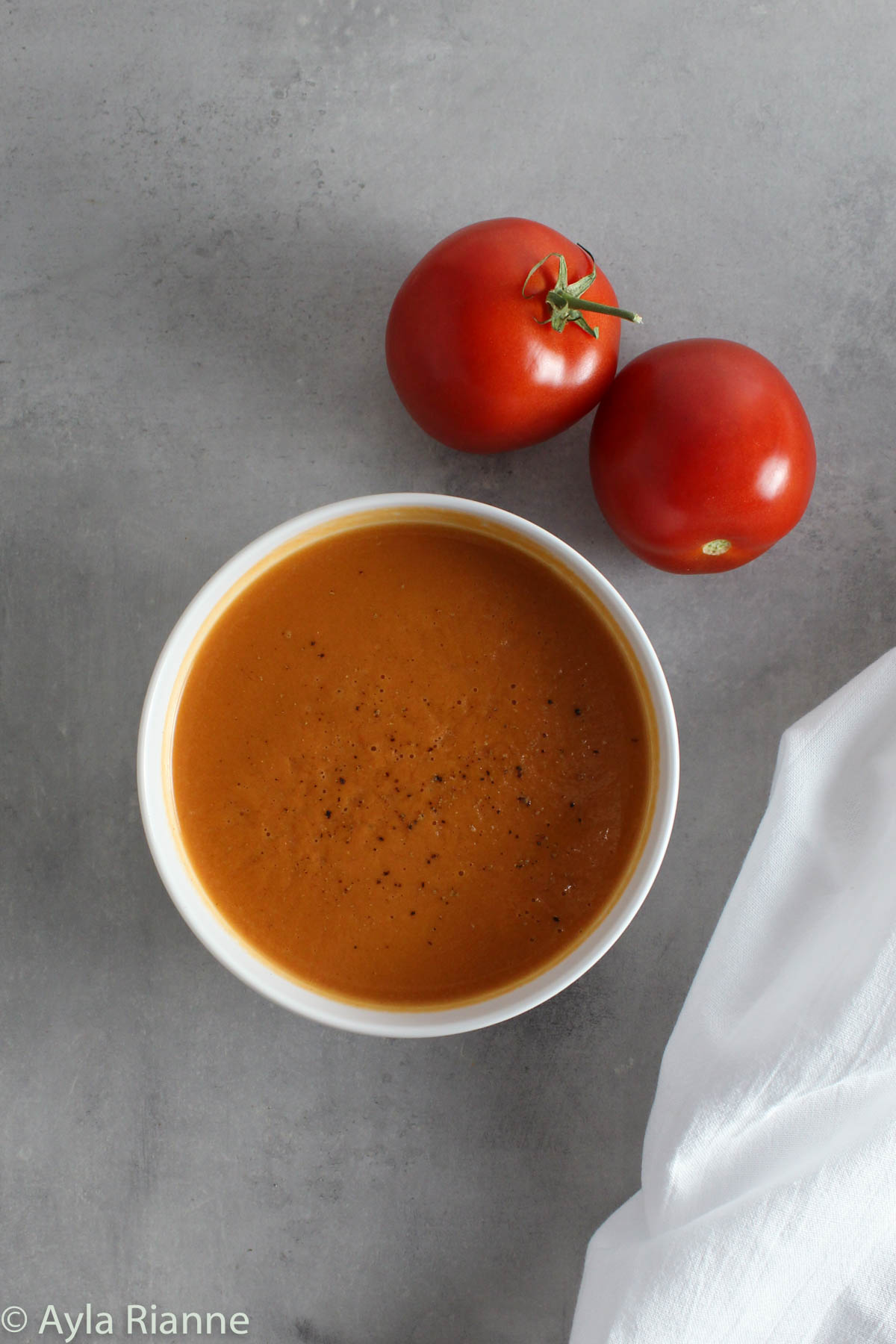 a bowl of tomato soup with two tomatoes