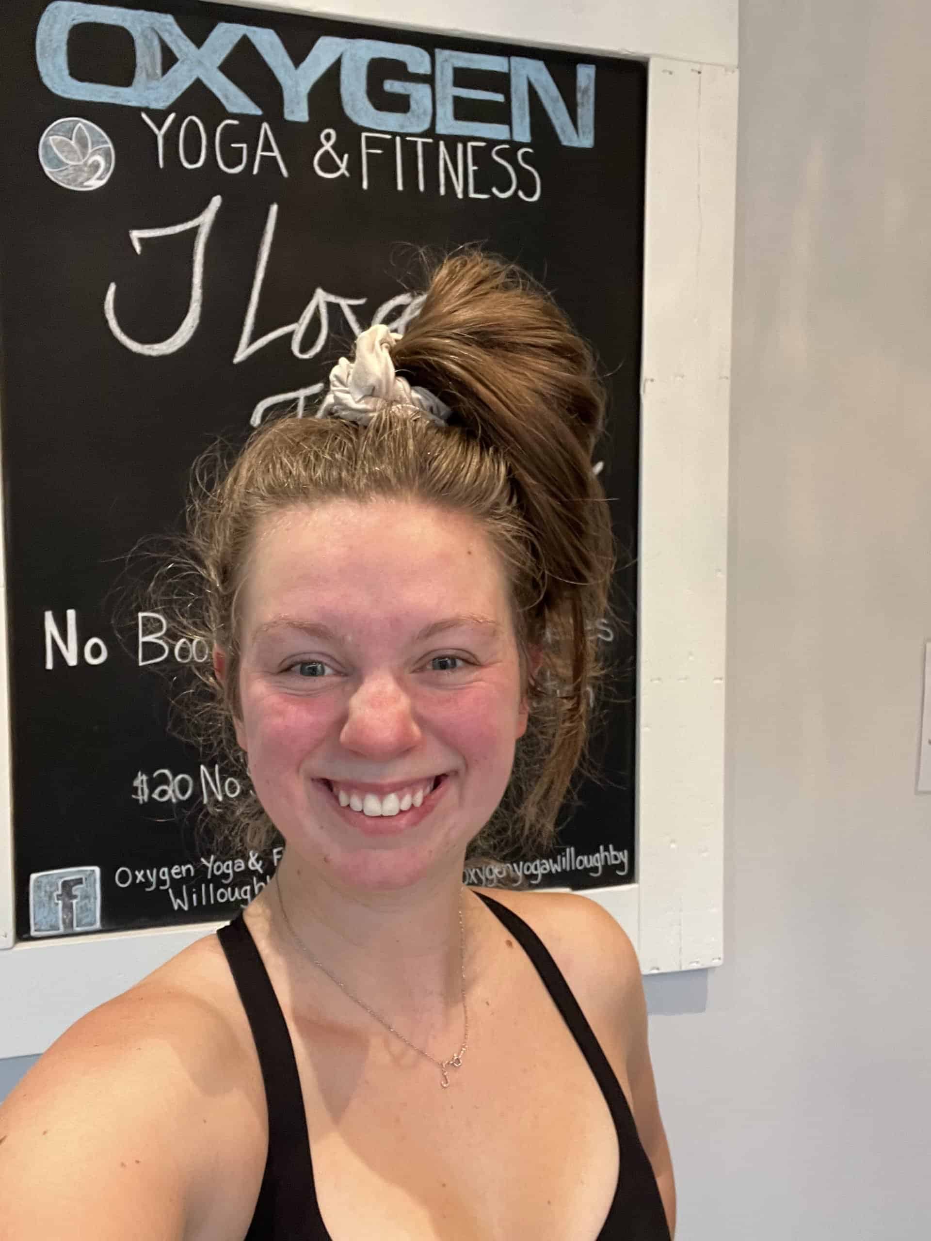 a smiling and sweaty women standing in front of a chalkboard