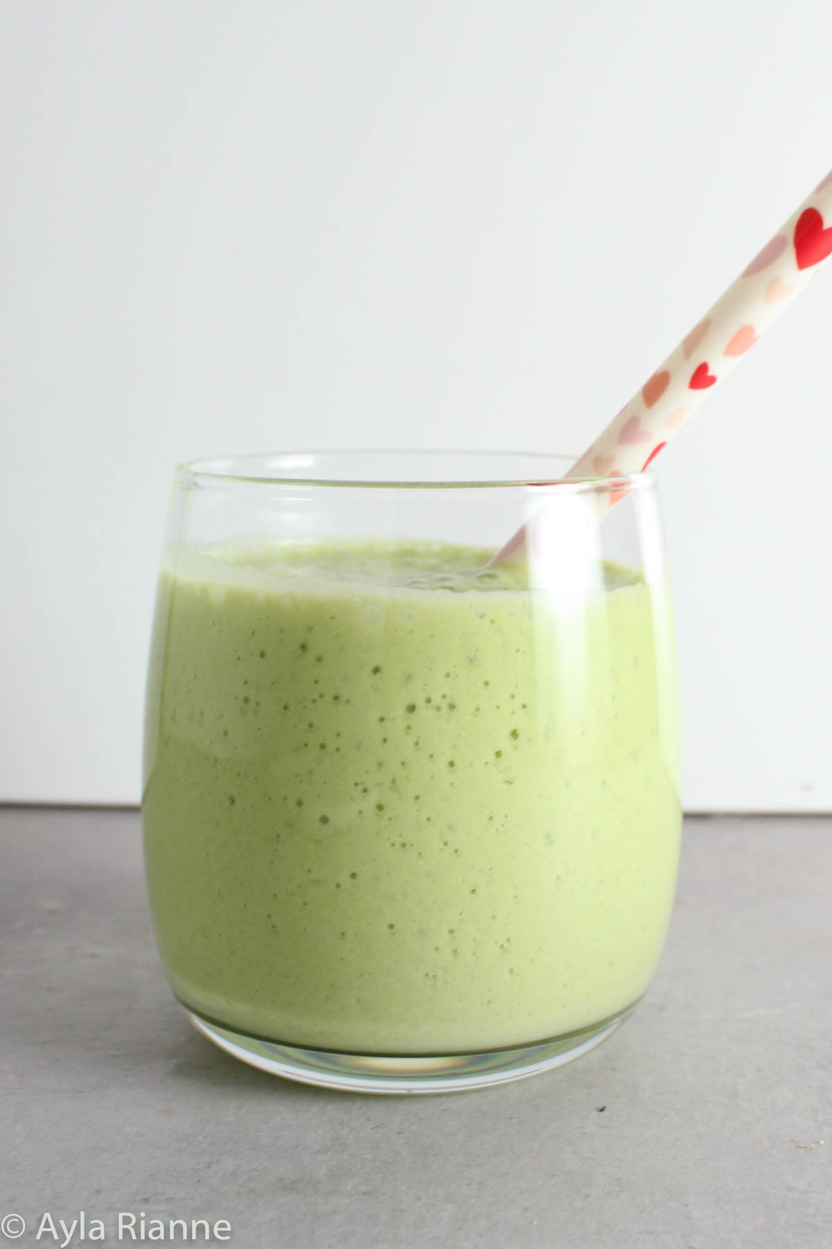 green smoothie in a glass with a straw