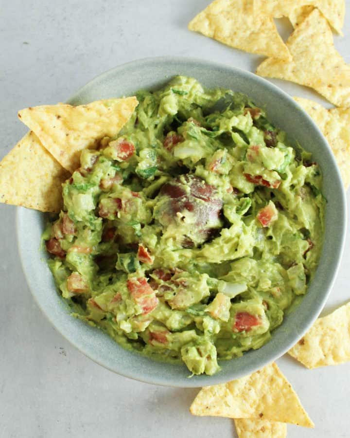 a bowl of guacamole with tortilla chips