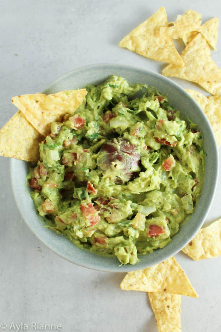 a bowl of guacamole with tortilla chips