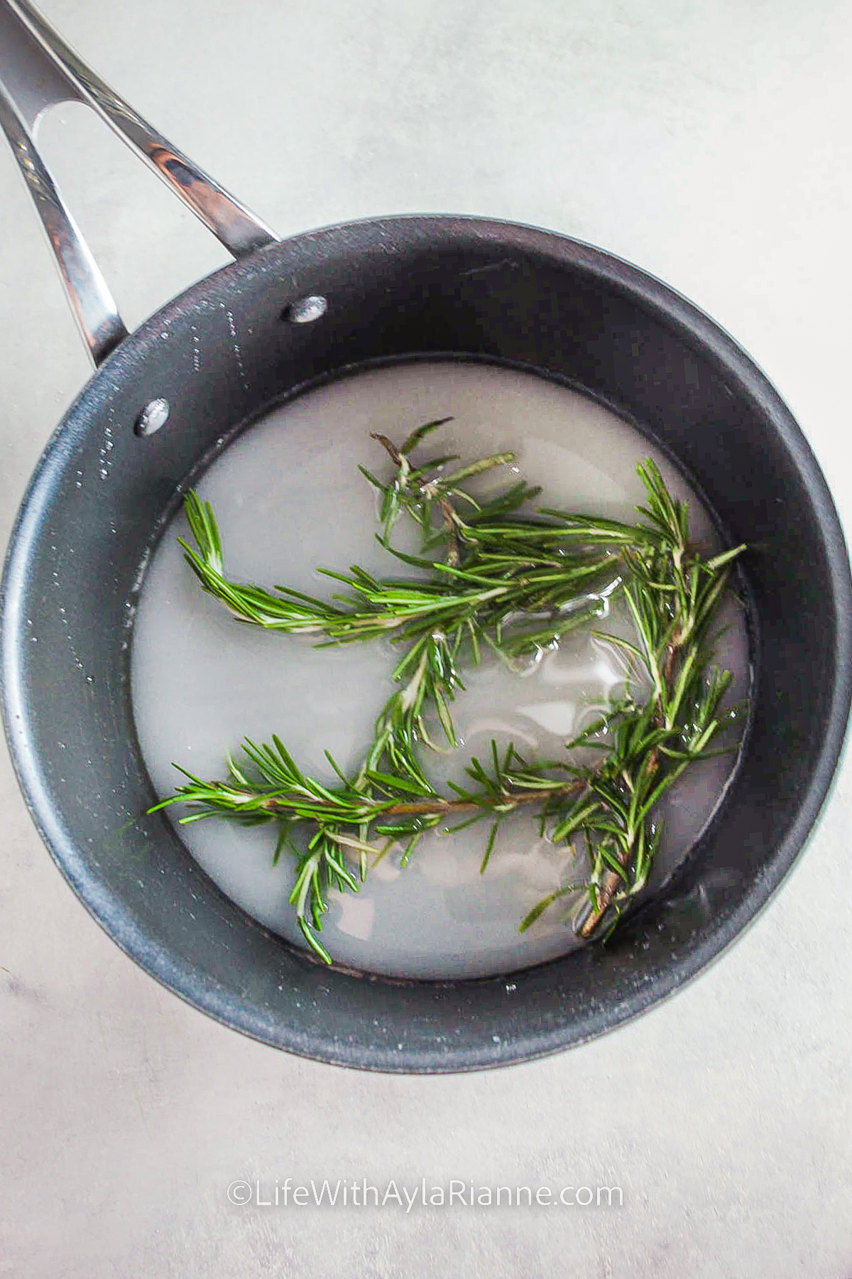 adding rosemary to pot to make Rosemary Simple Syrup