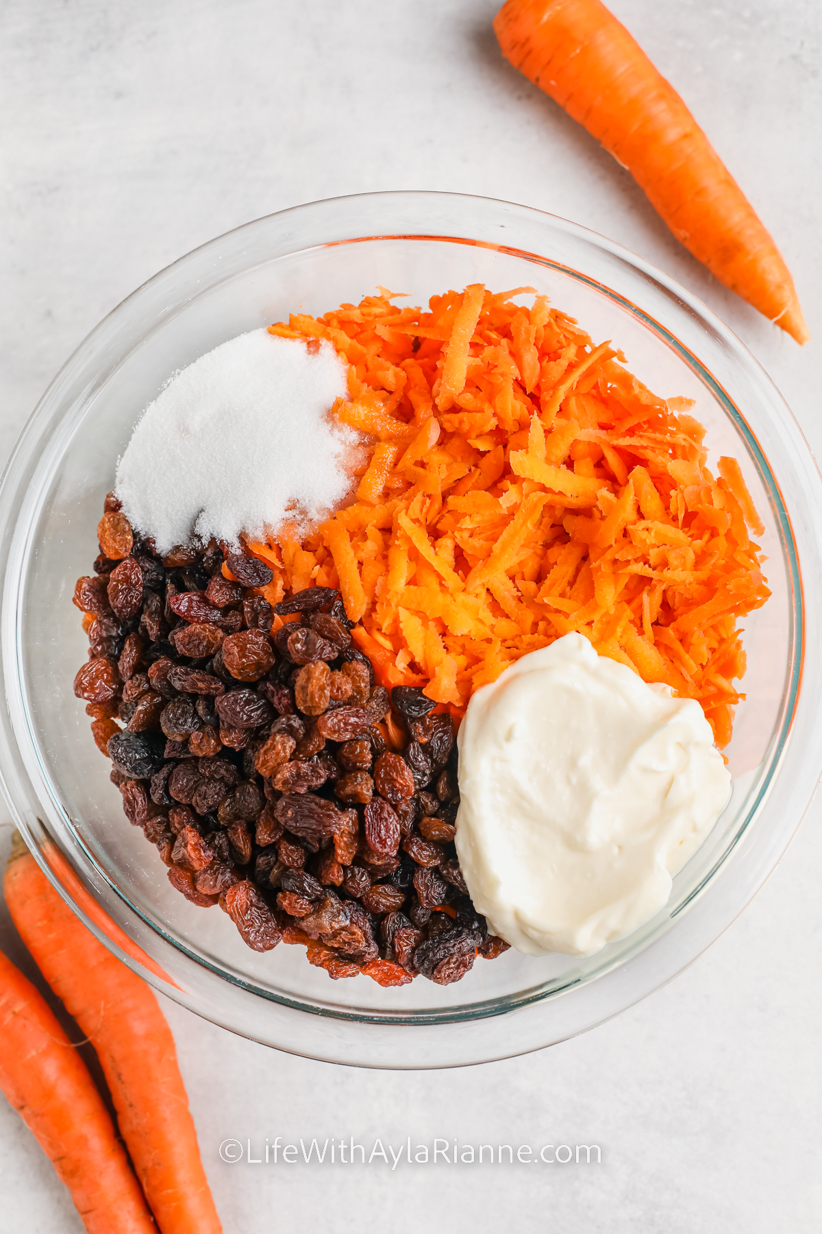 ingredients in a bowl to make Carrot and Raisin Salad