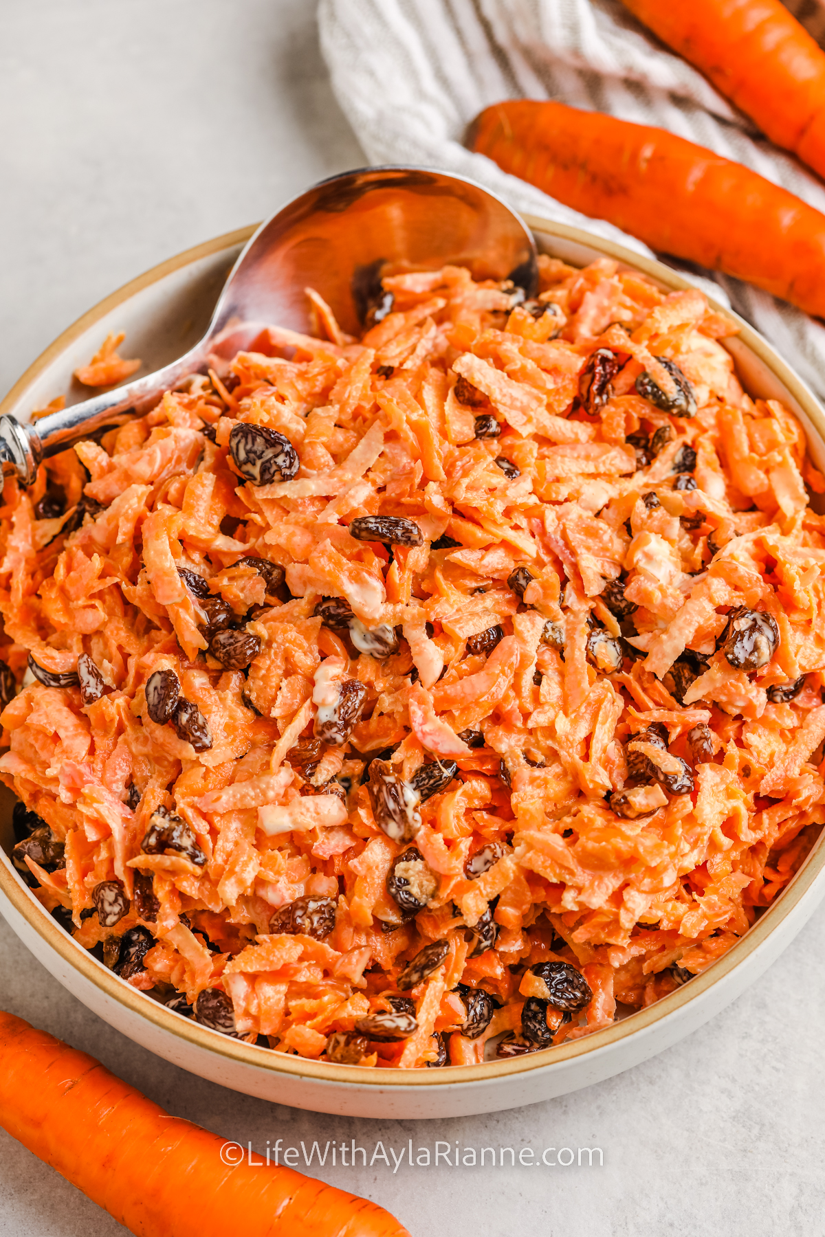 simple Carrot and Raisin Salad in a bowl with a spoon