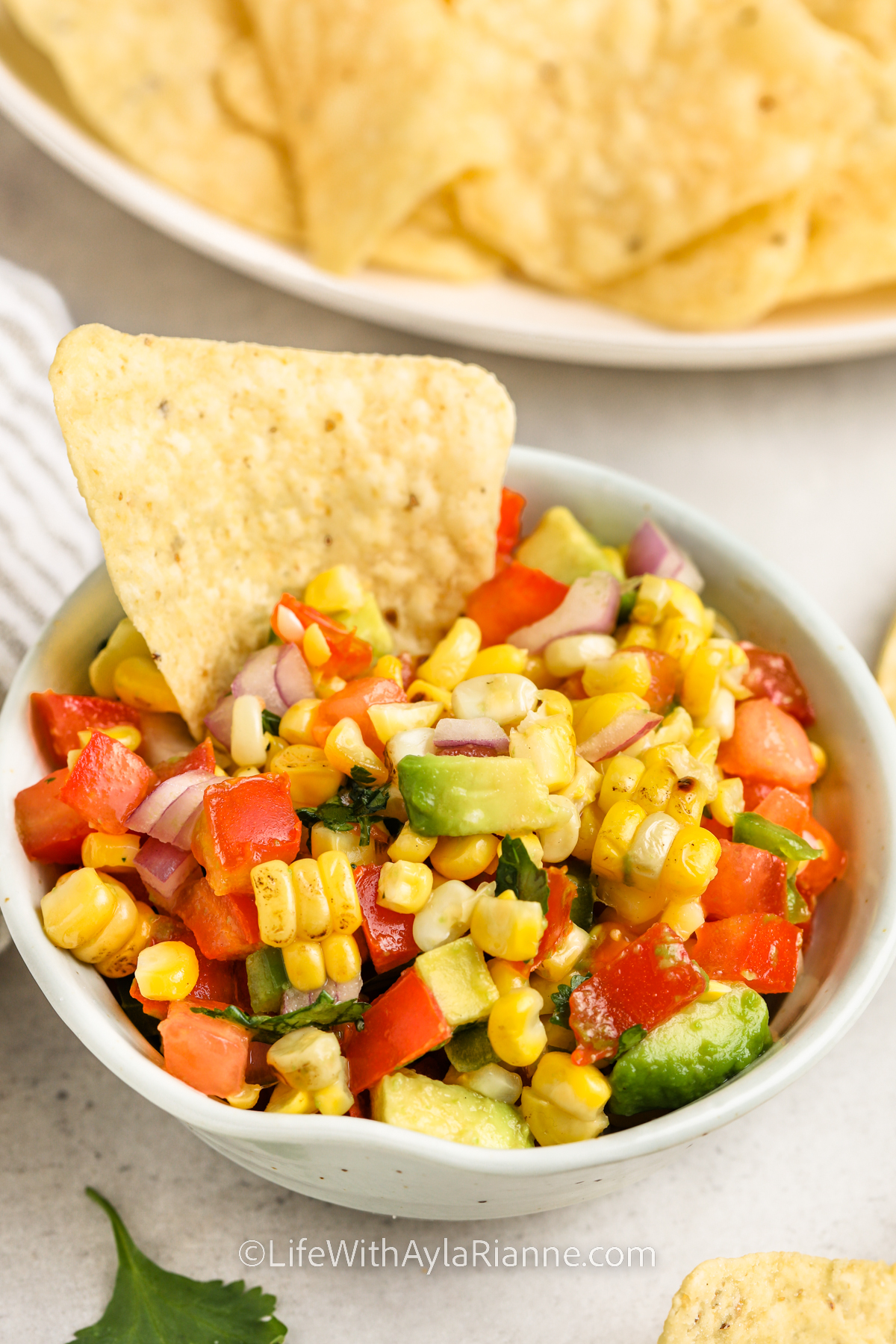Roasted Corn Salsa in a bowl with a chip
