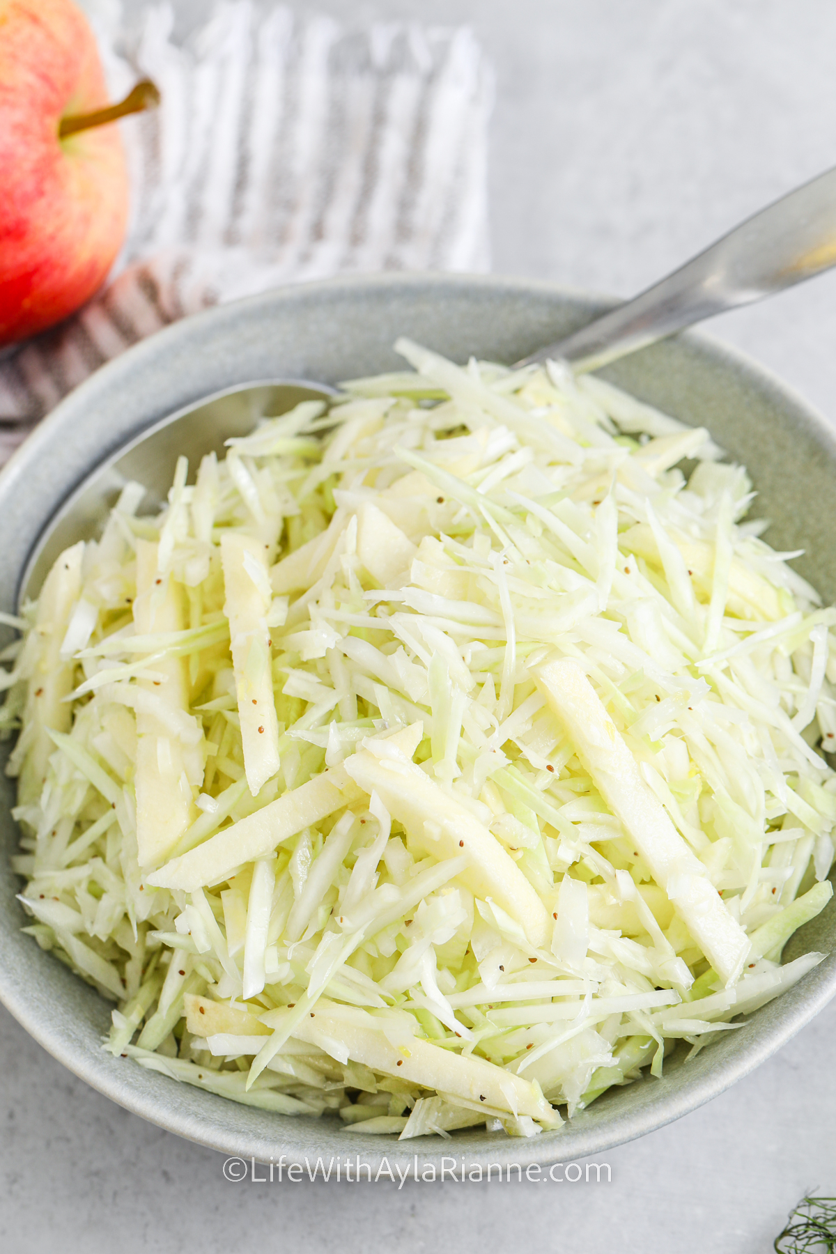 Apple Fennel Slaw in a serving bowl with a spoon