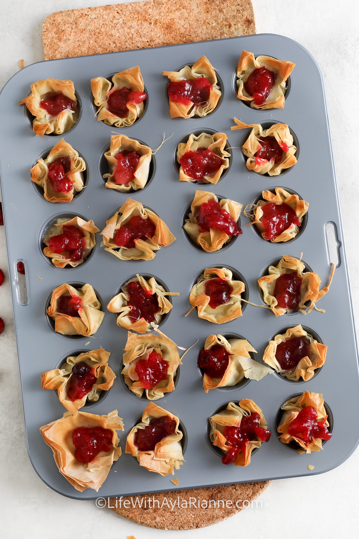 a muffin tin with Brie Cranberry Bites in each well