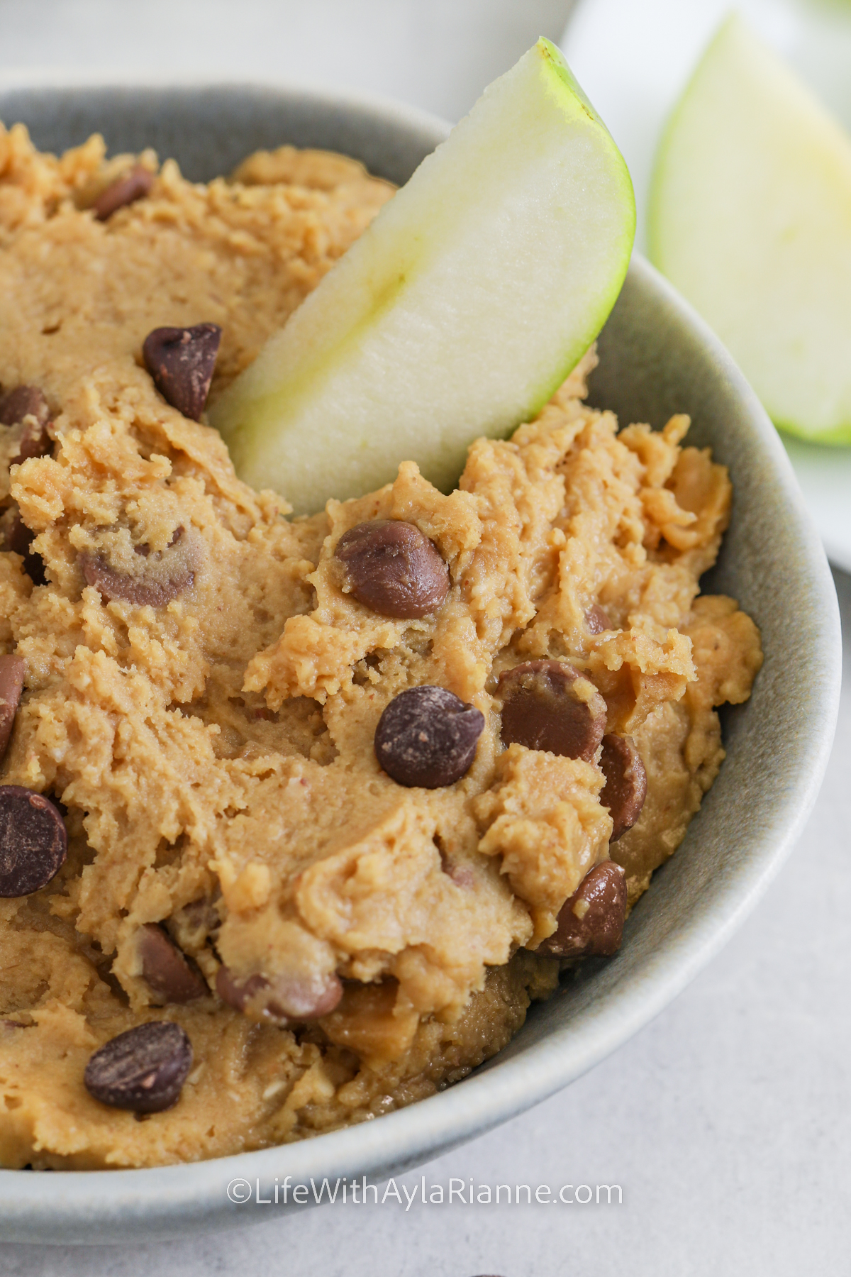 Chickpea Cookie Dough in a bowl with an apple slice