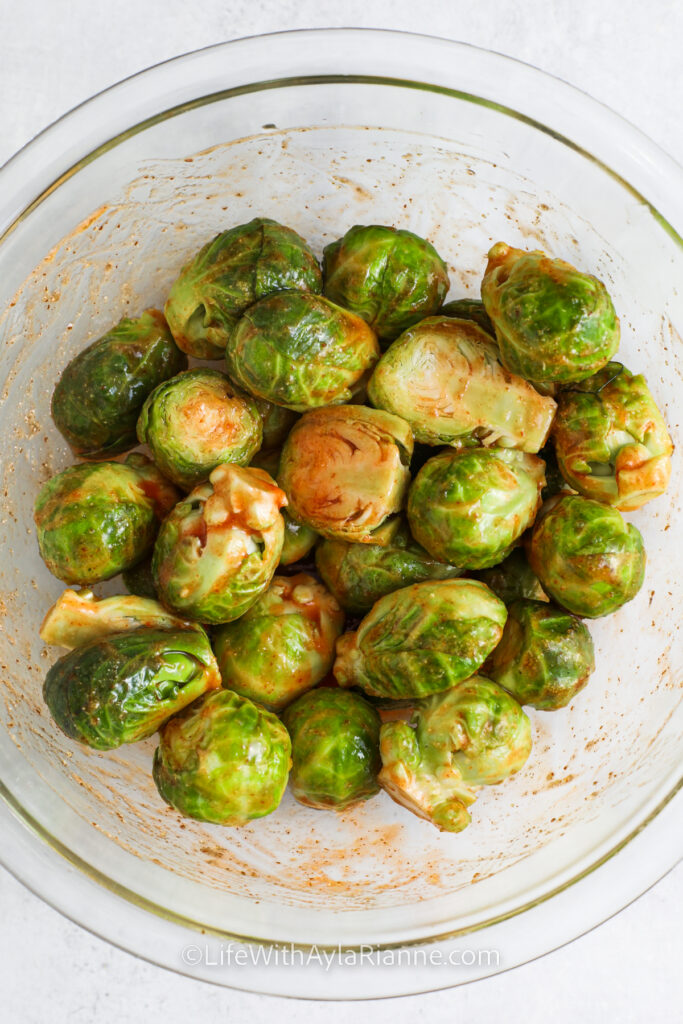 adding sauce to brussels to make Honey Sriracha Brussels Sprouts