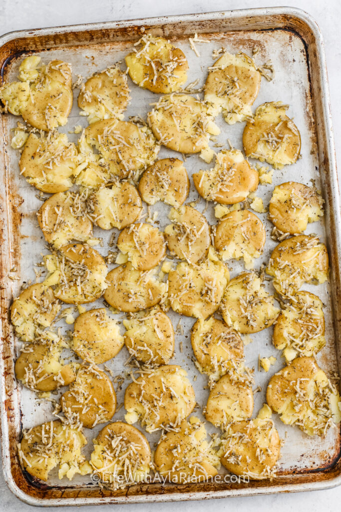 parmesan smashed potatoes on a sheet pan before being cooked