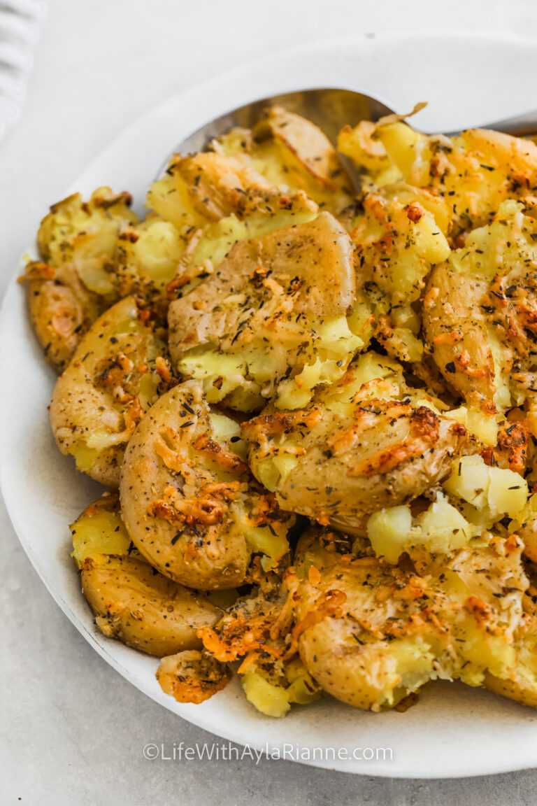 parmesan smashed potatoes on a plate with a serving spoon