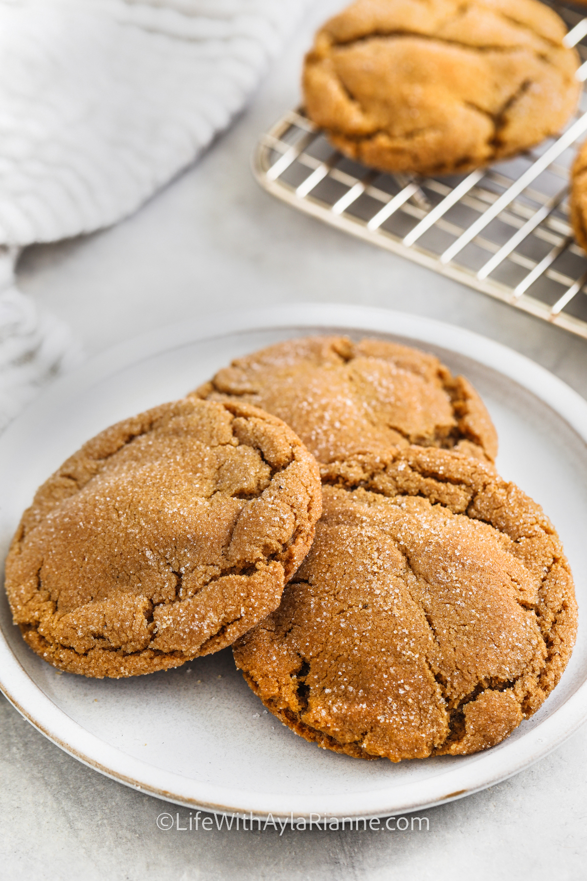 3 chewy gingersnap cookies on a white plate