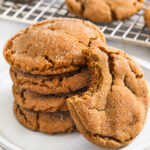 chewy gingersnap cookies on a white plate with a bite taken out of one