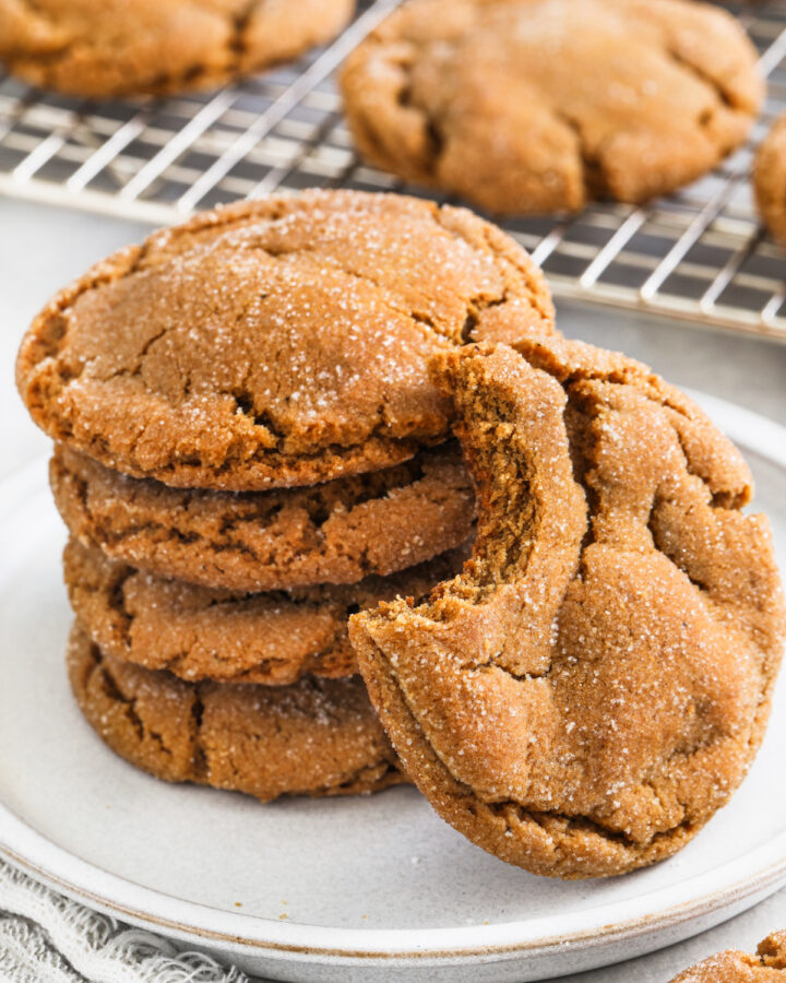 chewy gingersnap cookies on a white plate with a bite taken out of one