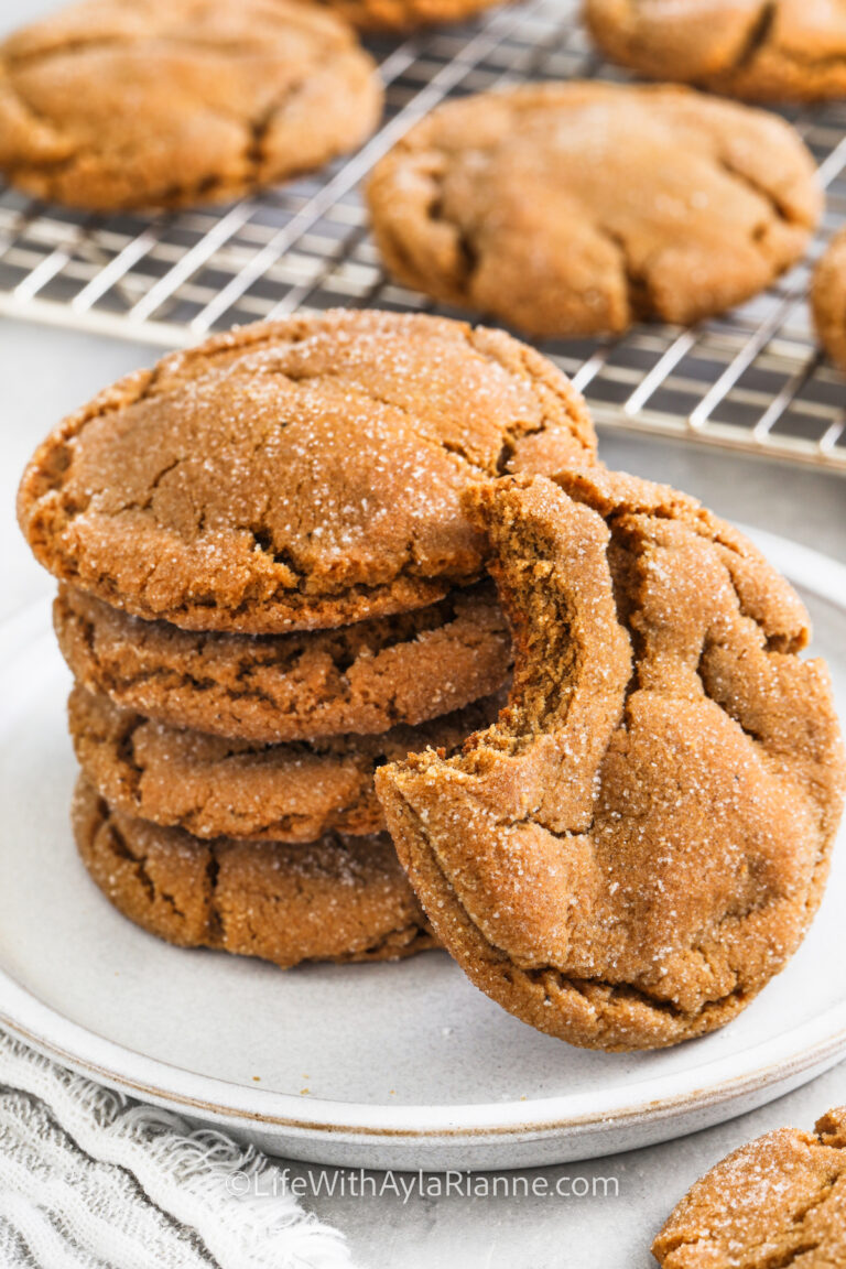 chewy gingersnap cookies on a white plate with a bite taken out of one