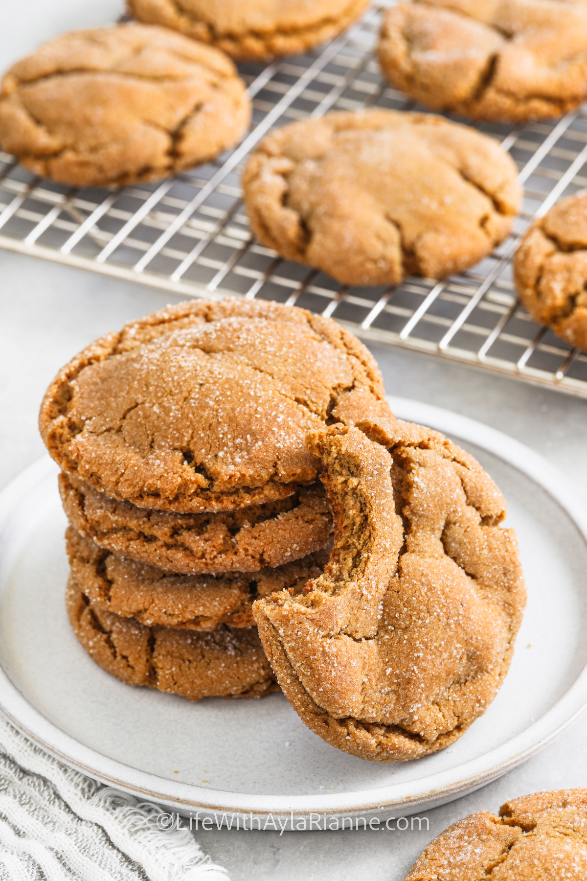 chewy gingersnap cookies on a plate with a bite taken from one cookie