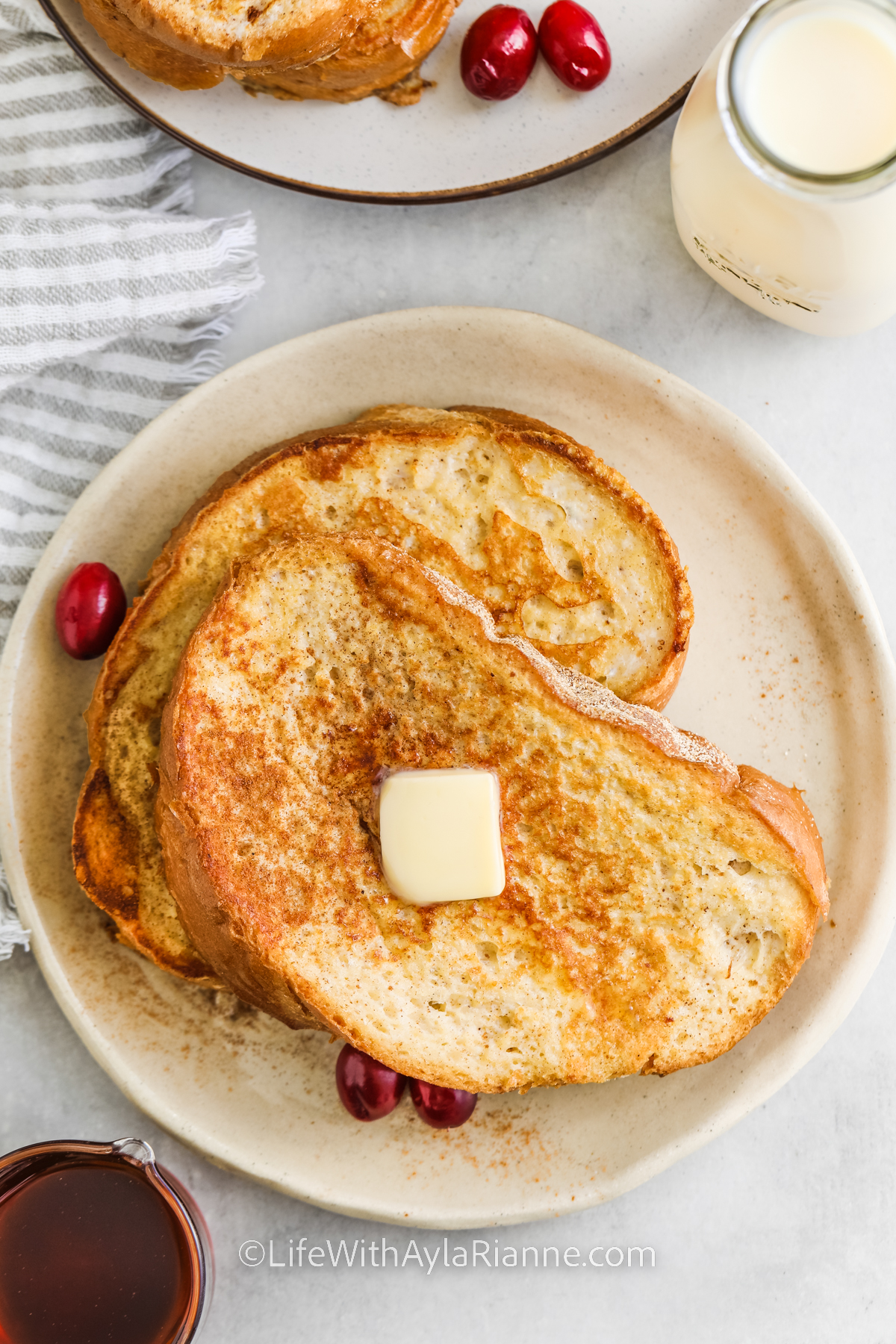 Eggnog French Toast on a plate with butter and cranberries