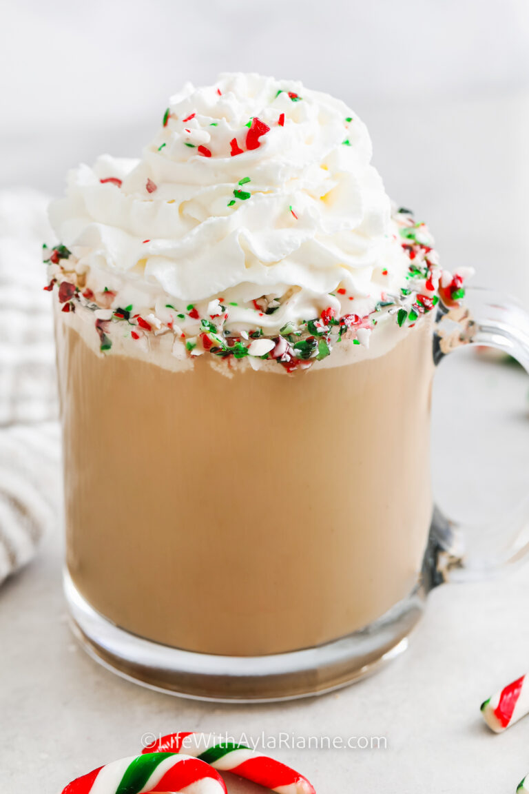 peppermint latte in a clear mug with whipped cream and crushed candy canes