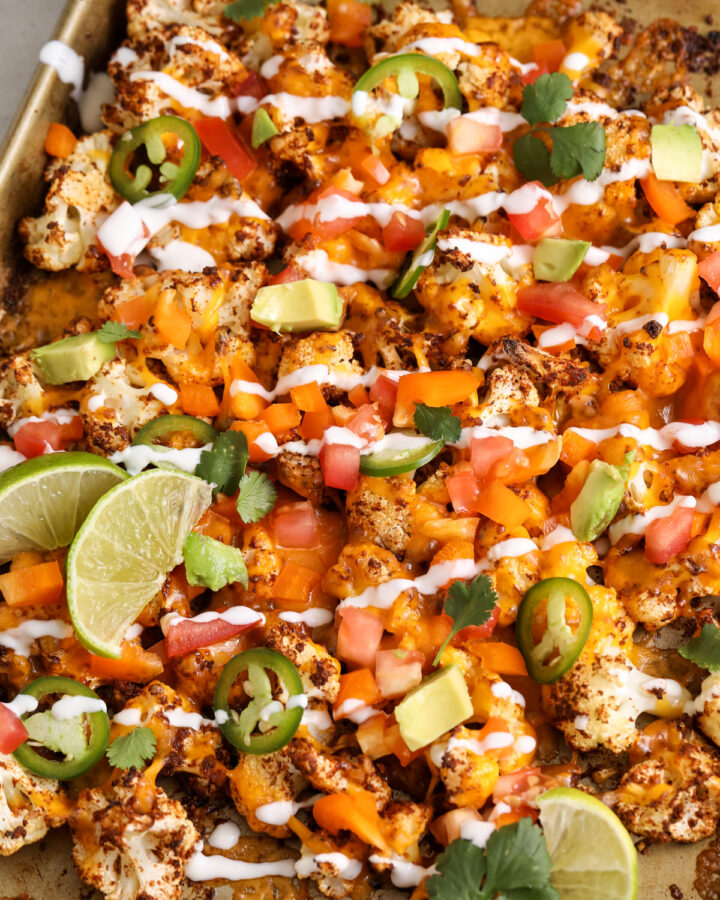 Cauliflower Nachos on a baking sheet drizzled with sauce