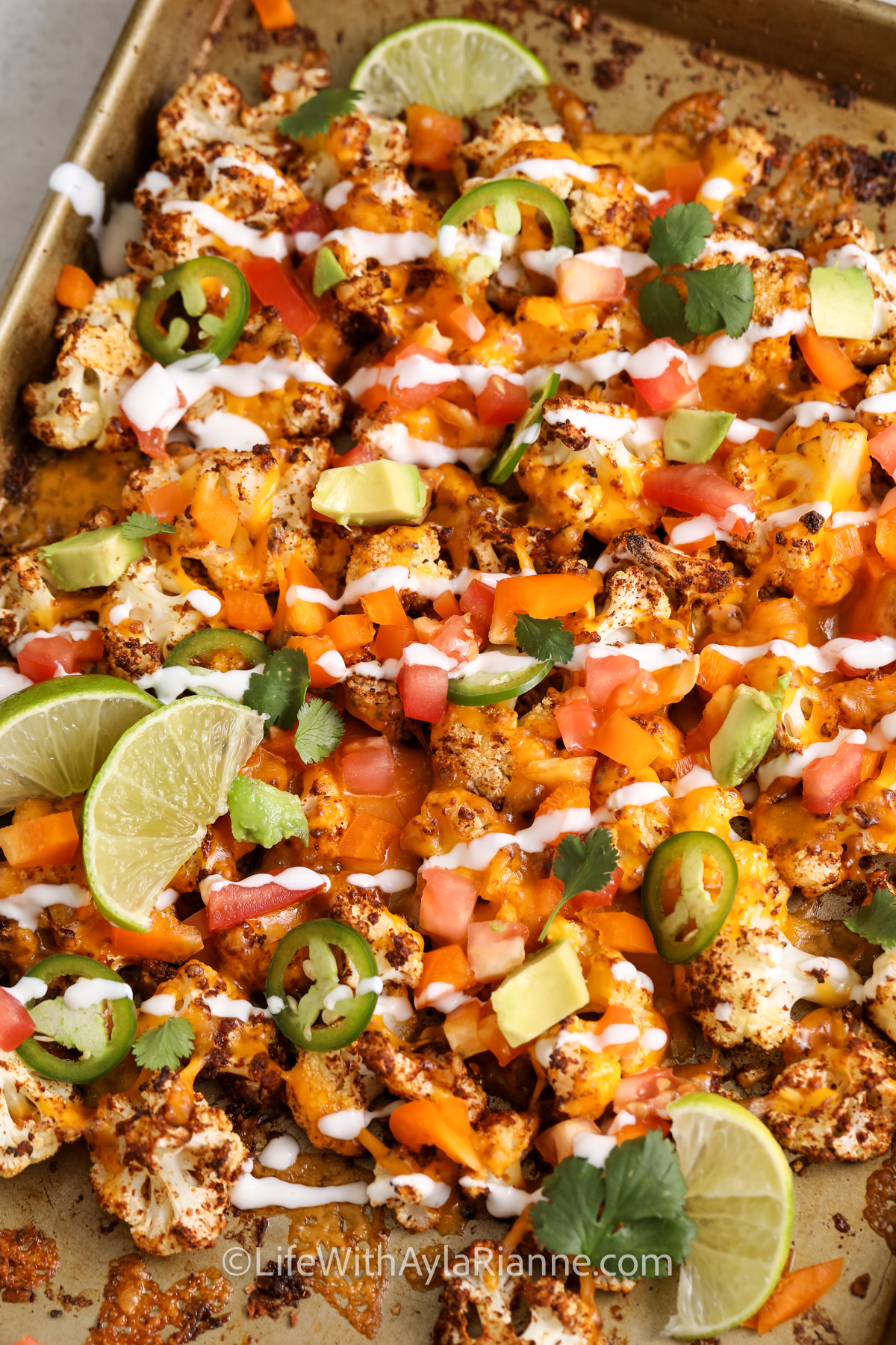 Cauliflower Nachos on a baking sheet drizzled with sauce