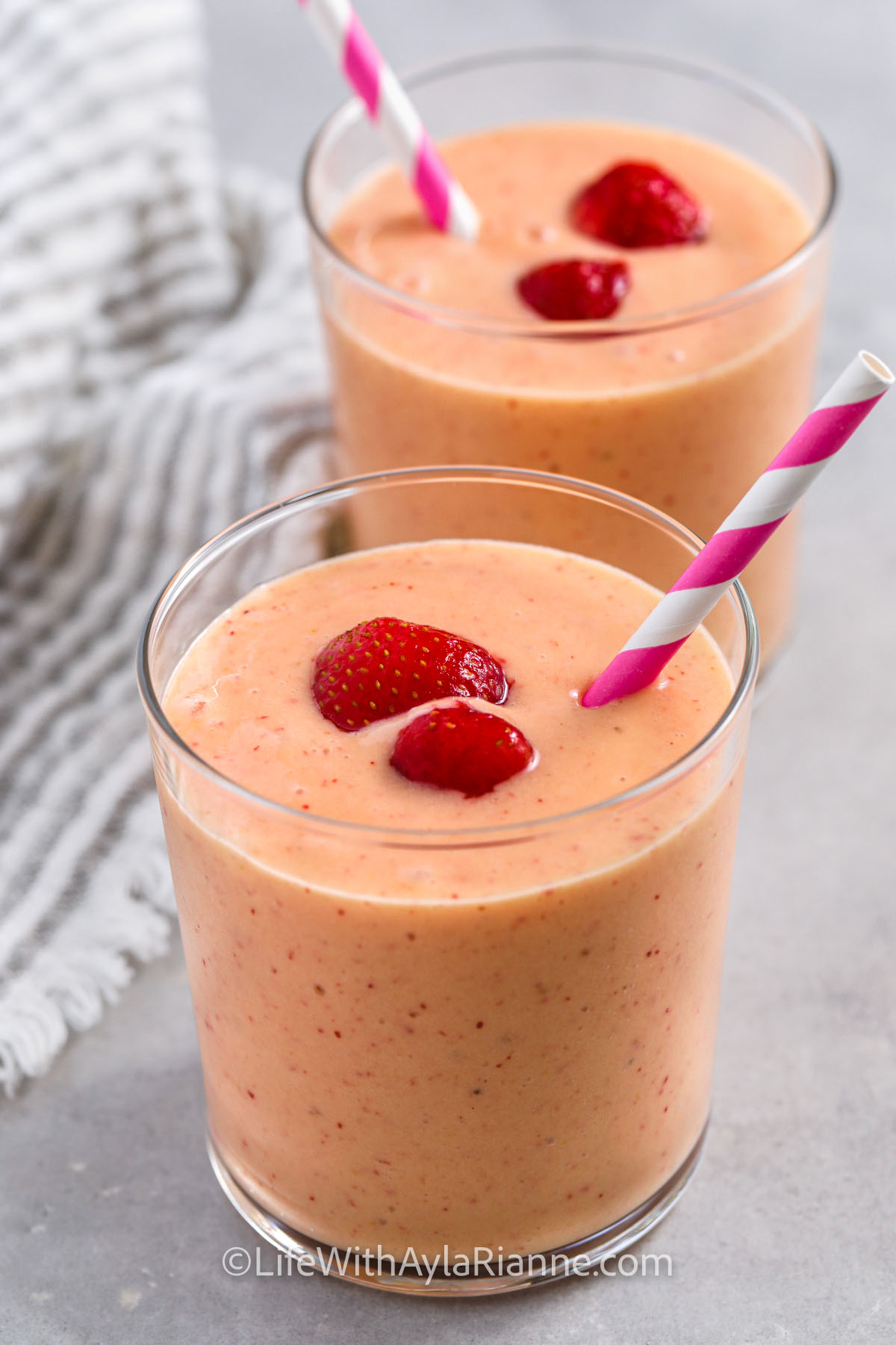 Strawberry Mango Smoothies in a glass with strawberries and straws