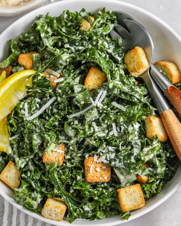 Kale Caesar Salad in a bowl with serving utensils