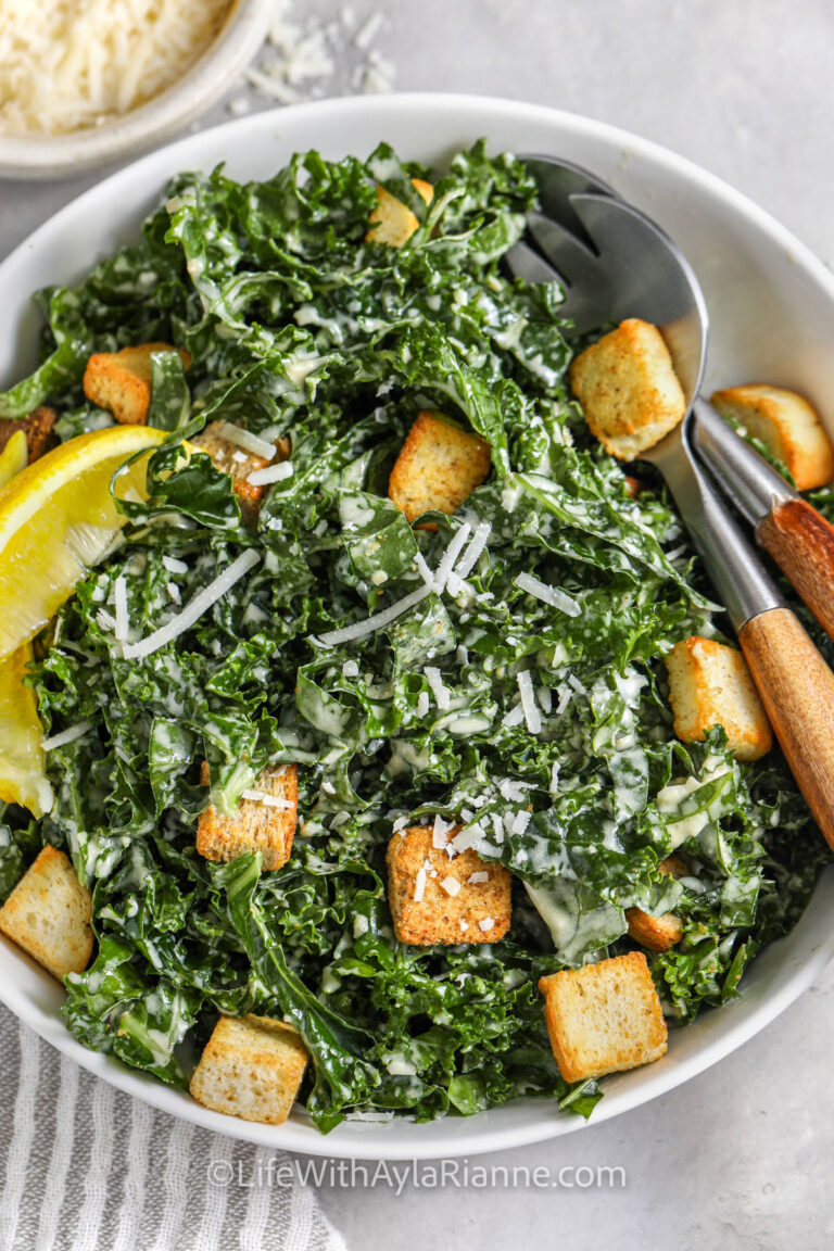 Kale Caesar Salad in a bowl with serving utensils