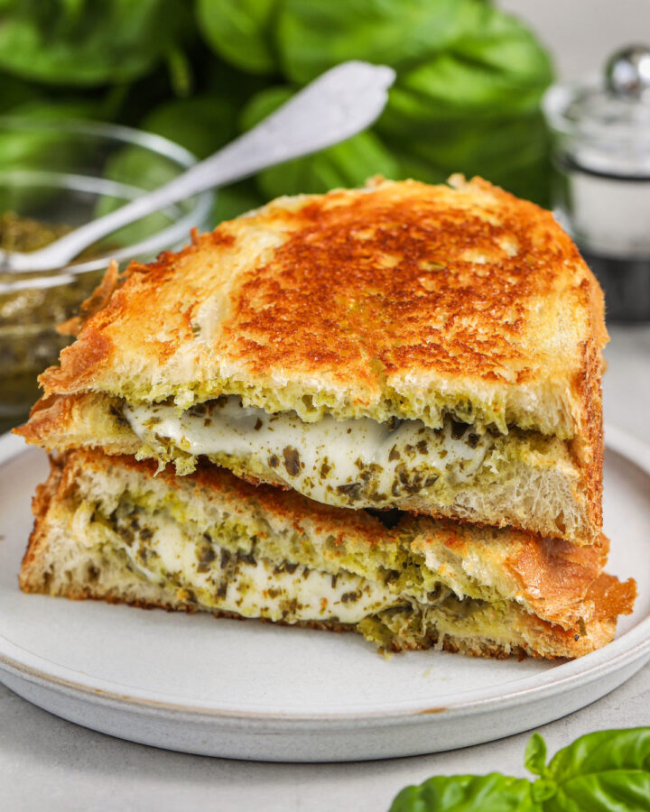 pesto grilled cheese on a white plate cut in half
