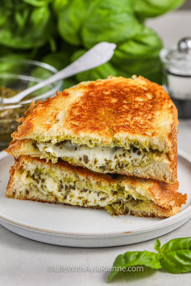 pesto grilled cheese on a white plate cut in half