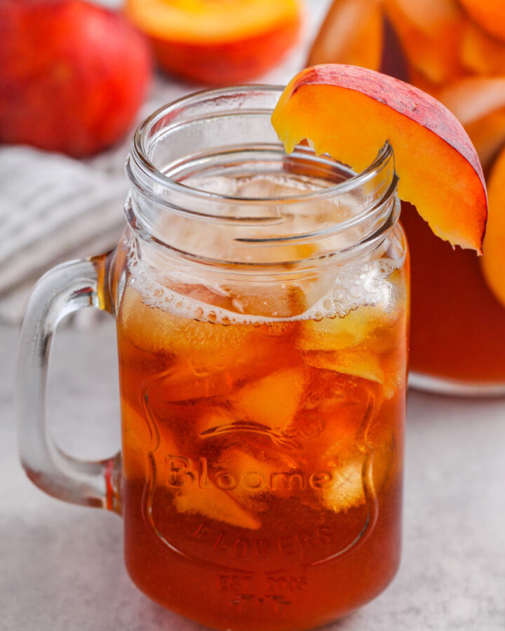 Peach Iced Tea in a glass with a sliced peach on the rim