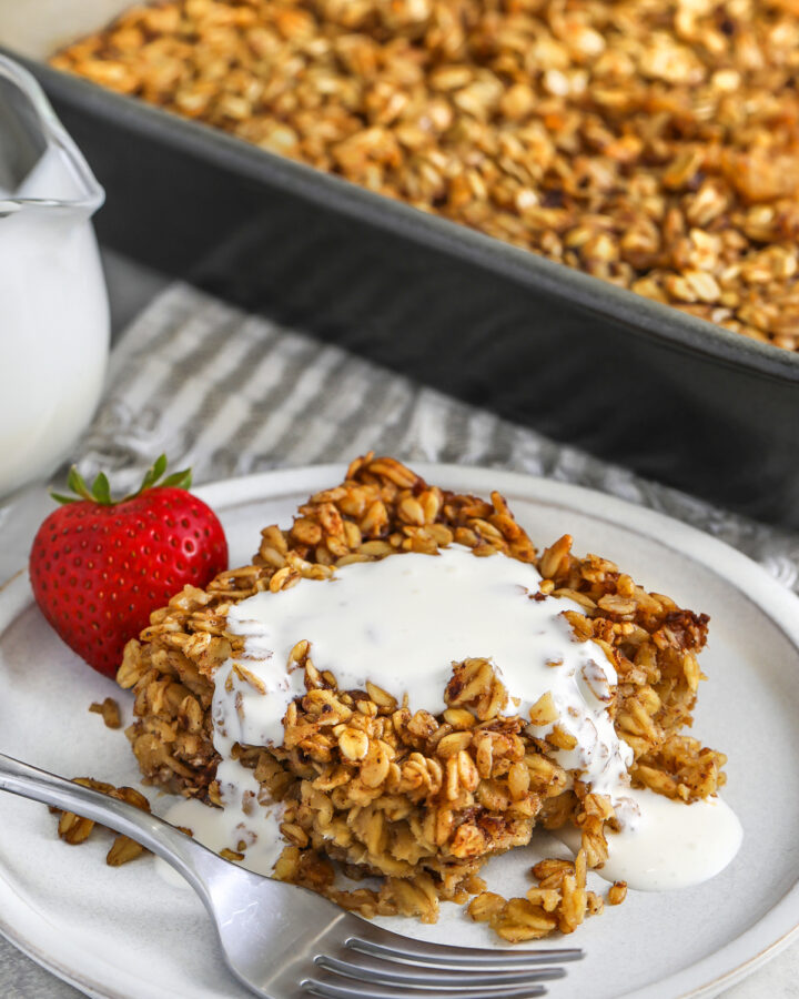 slice of Baked Oatmeal on a plate with cream and strawberries