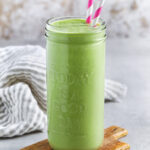 glass of Tropical Green Smoothie with pink striped straws