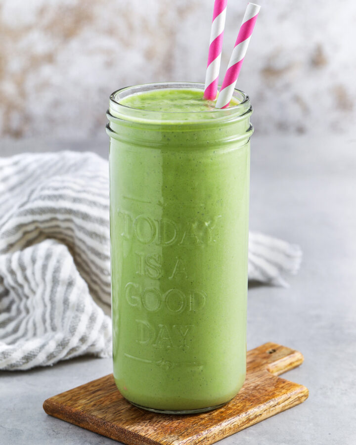 glass of Tropical Green Smoothie with pink striped straws