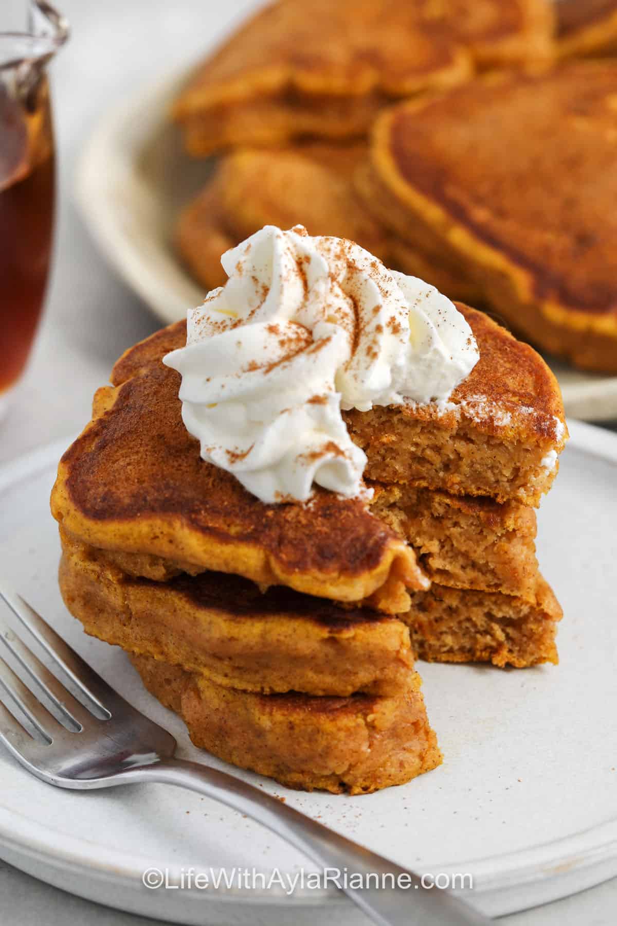 close up of Fluffy Pumpkin Pancakes with whipped cream on top